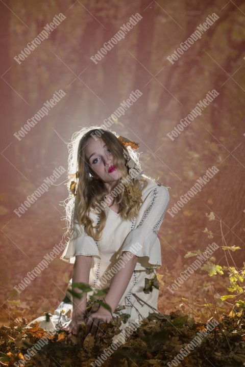 Beautiful young woman in white dress enjoying autumn park.