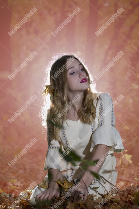 Beautiful young woman in white dress enjoying autumn park