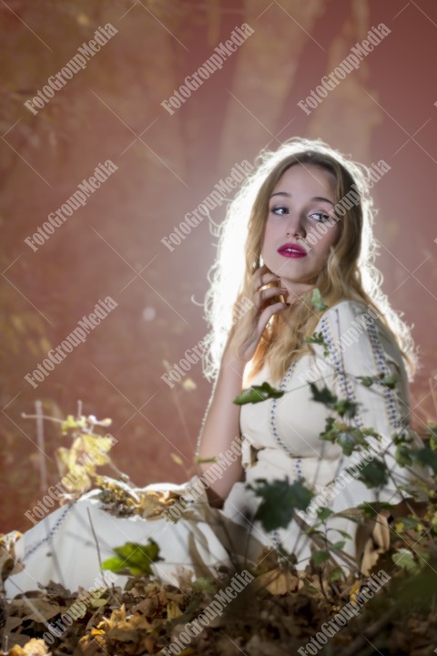 Beautiful young woman in white dress enjoying autumn park