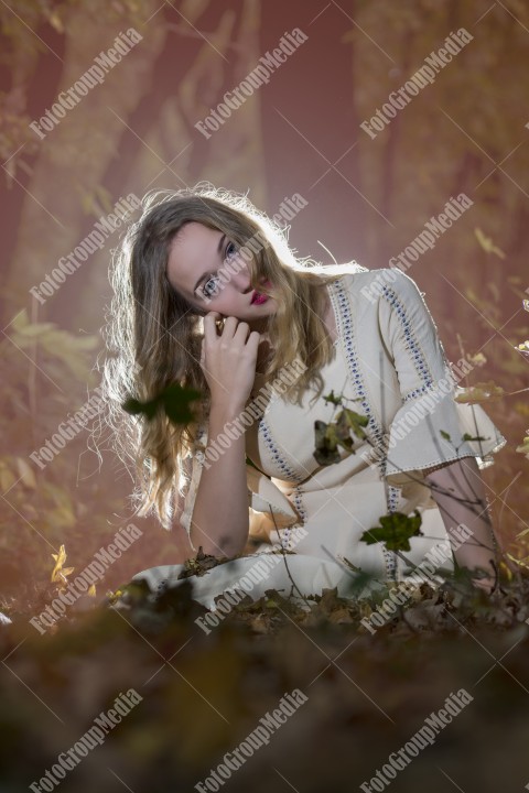 Beautiful young woman in white dress enjoying autumn park