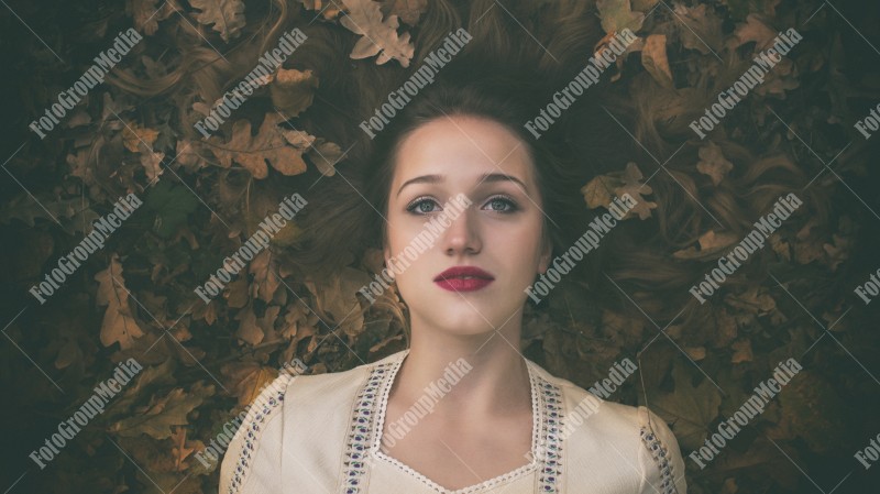 Young woman laying on a bed of dry leafs