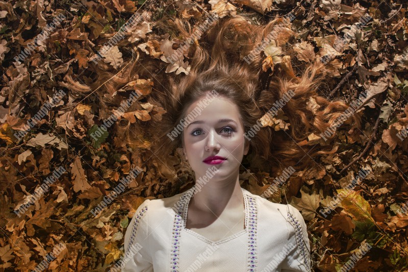 Young woman laying on a bed of dry leafs