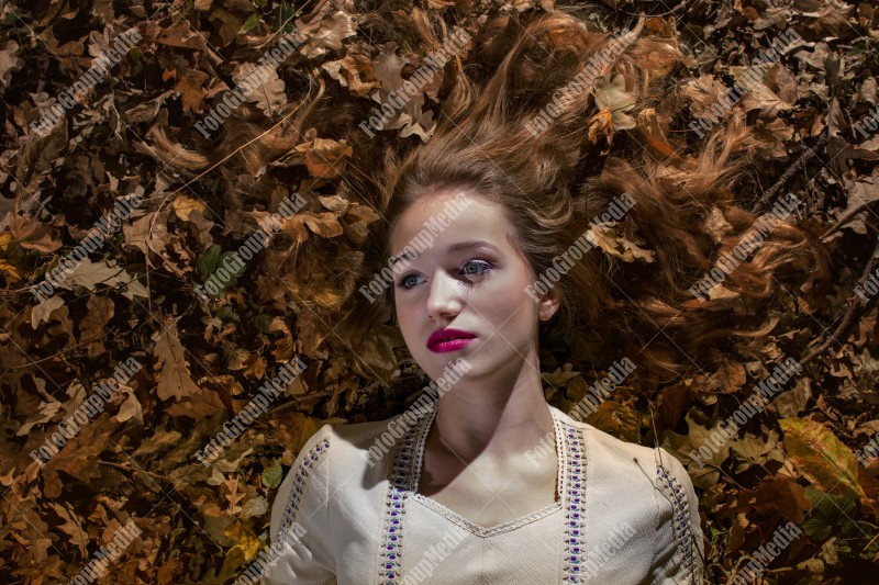 Young woman laying on a bed of dry leafs