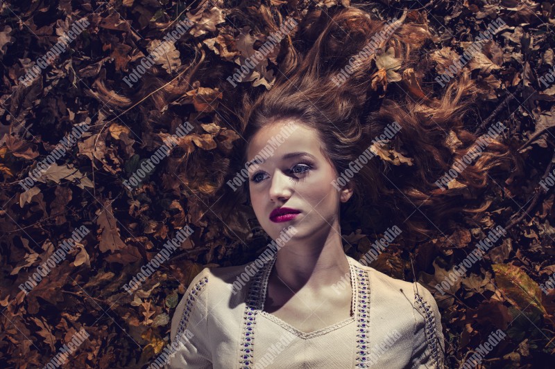 Young woman laying on a bed of dry leafs