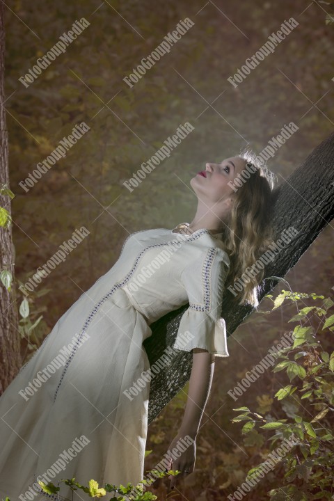 Natural beauty of a woman in a white dress laying on a tree