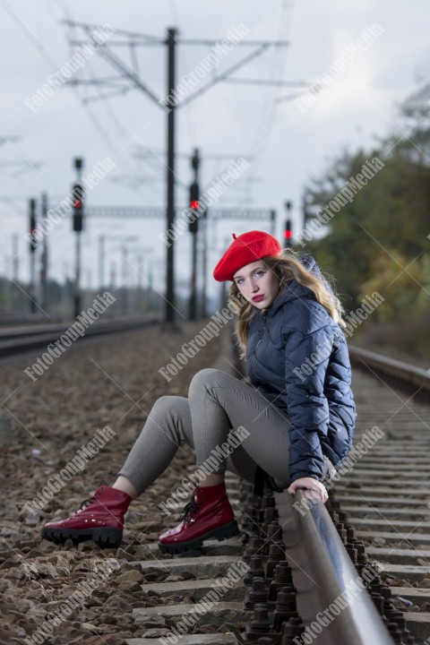 Young beautiful girl sitting on railroad track