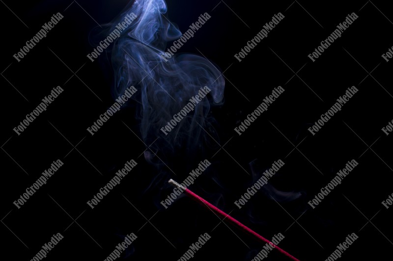 Blue smoke incense stick on black background.