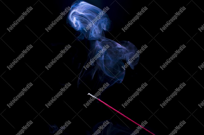 Blue smoke incense stick on black background