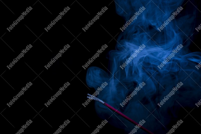 Blue smoke incense stick on black background