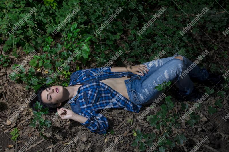 Yound woman dressed in plaid shirt and jeans posing outdoor