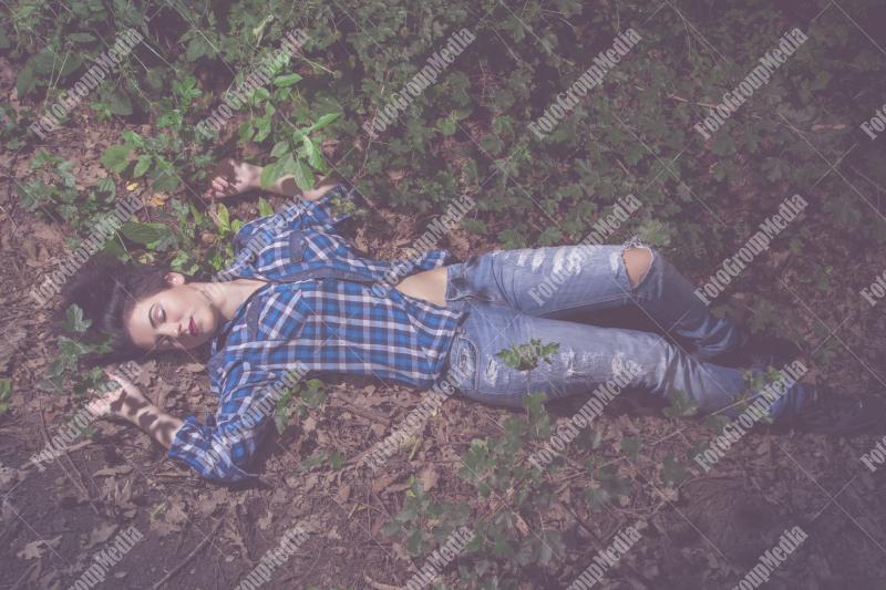 Yound woman dressed in plaid shirt and jeans posing outdoor