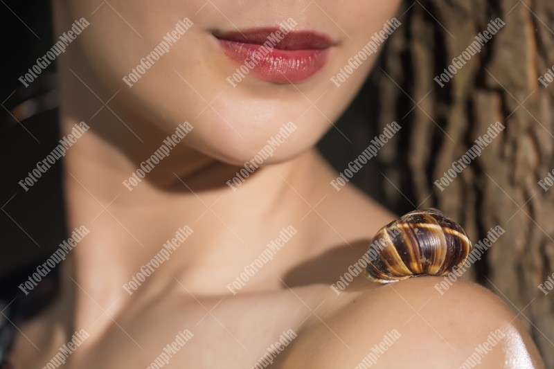 Close up of young girl face and snail on her shoulder