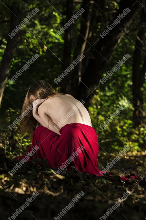 A shy woman cradles her body, facing away from the camera.