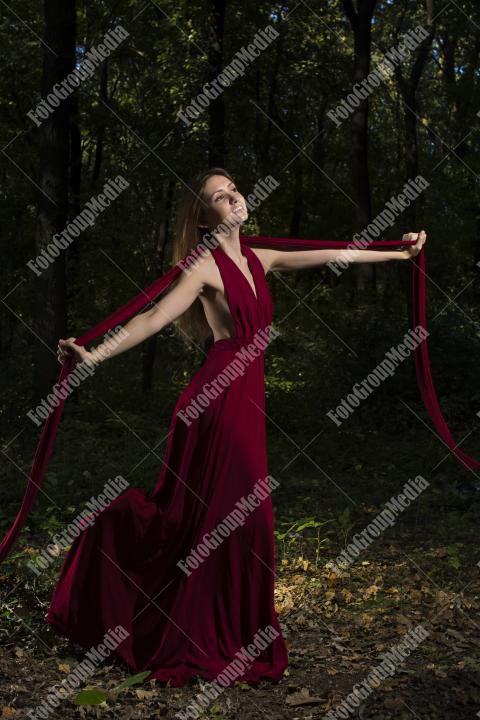 Brunette woman in red dress posing on forest background
