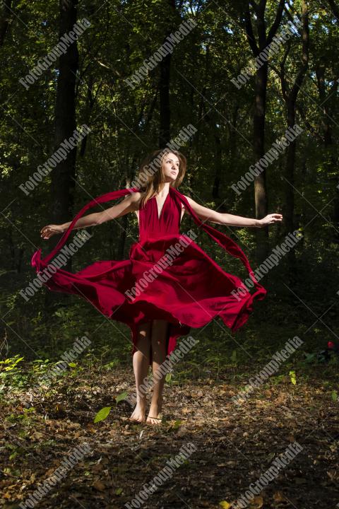 Brunette woman in red dress posing on forest background