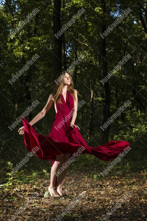 Brunette woman in red dress posing on forest background