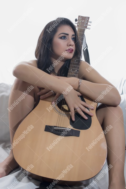 Pretty girl covering her body with guitar