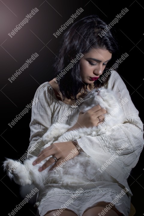 Portrait of young woman with cat on black background