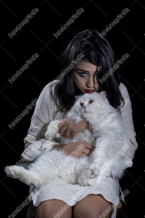 Portrait of young woman with cat on black background