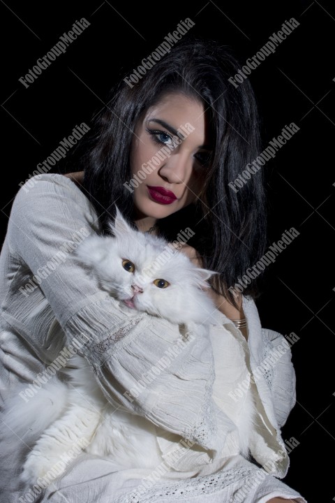 Portrait of young woman with cat on black background