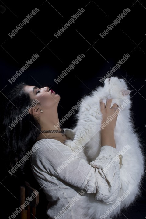 Portrait of young woman with cat on black background