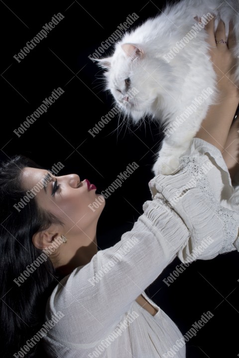 Portrait of young woman with cat on black background