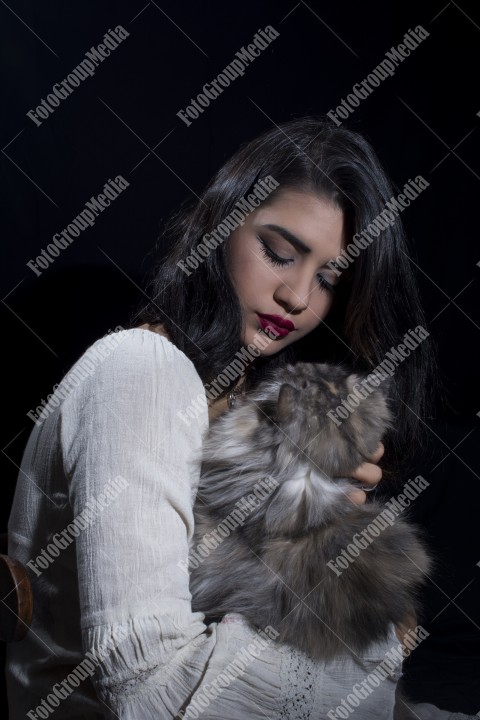 Portrait of young woman with cat on black background