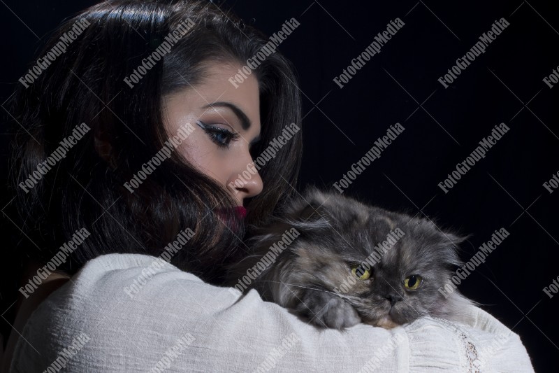 Portrait of young woman with cat on black background