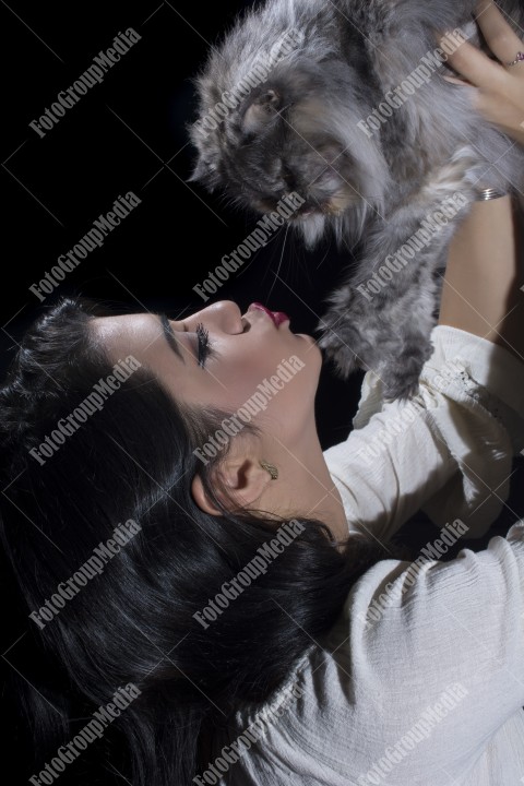 Portrait of young woman with cat on black background