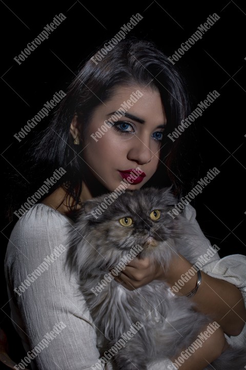 Portrait of young woman with cat on black background