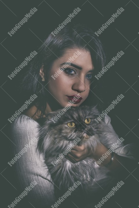 Portrait of young woman with cat on black background