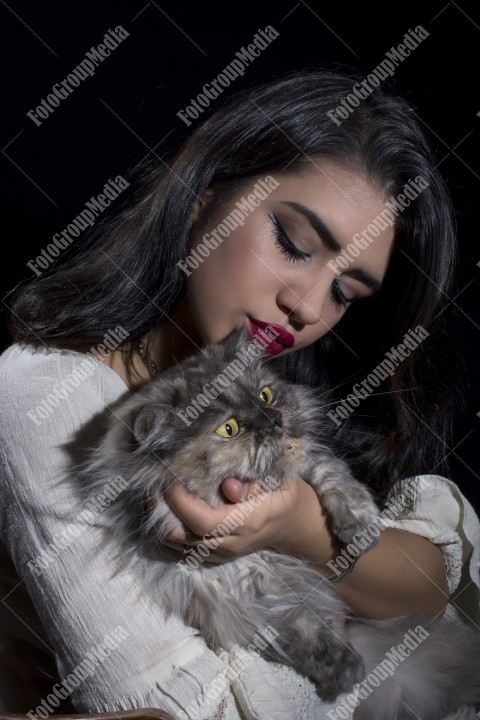 Portrait of young woman with cat on black background