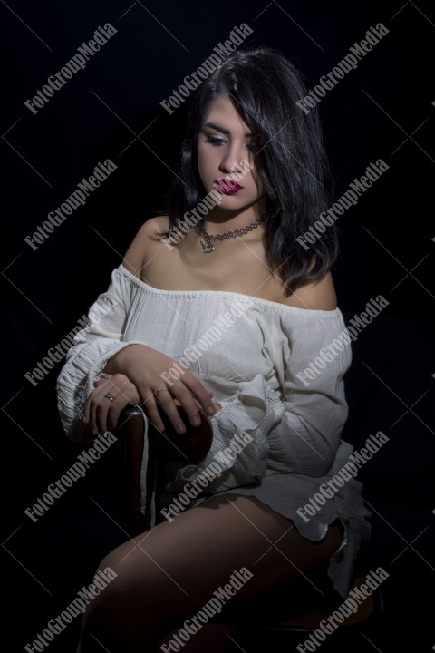 Fashion model posing in studio wearing white dress