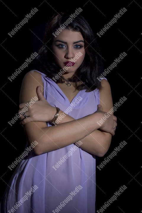 Fashion model posing in studio wearing purple dress on blac