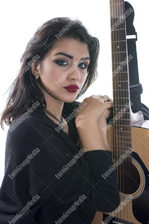 Brunette young girl and guitar posing in studio