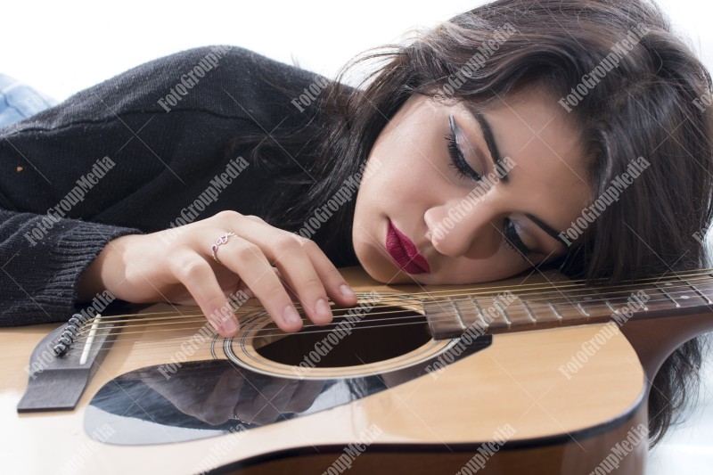 Brunette young girl and guitar posing on bed