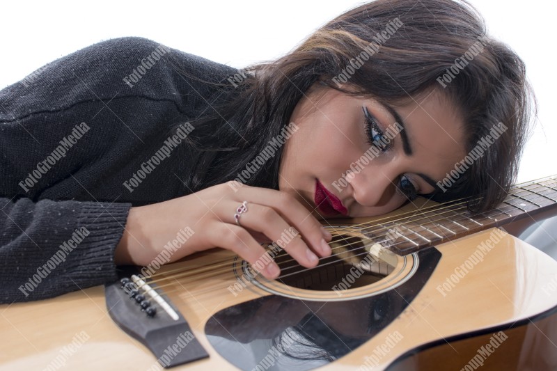 Brunette young girl and guitar posing on bed