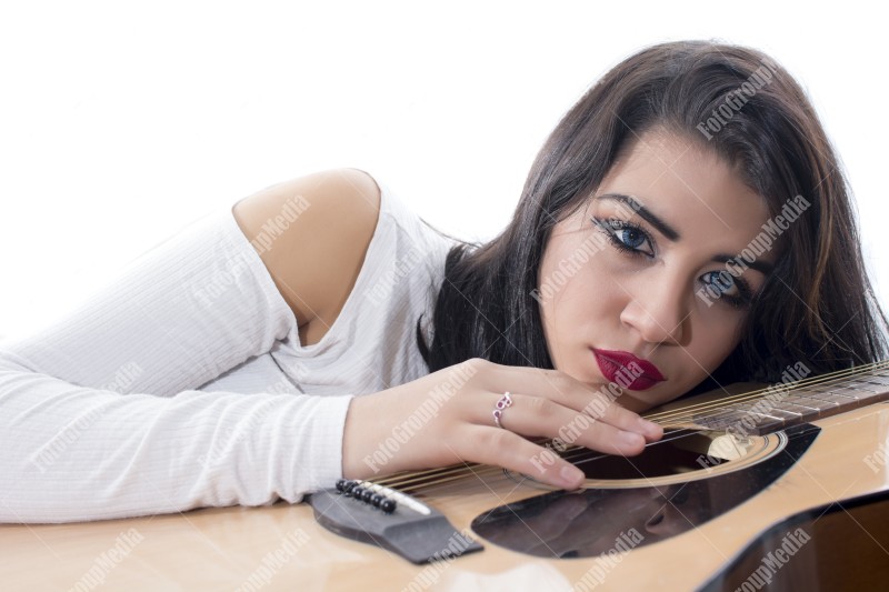 Brunette young girl and guitar posing on bed