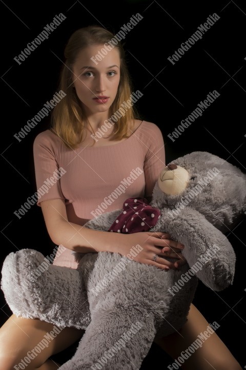 Young beautiful girl playing with her big huge teddy bear