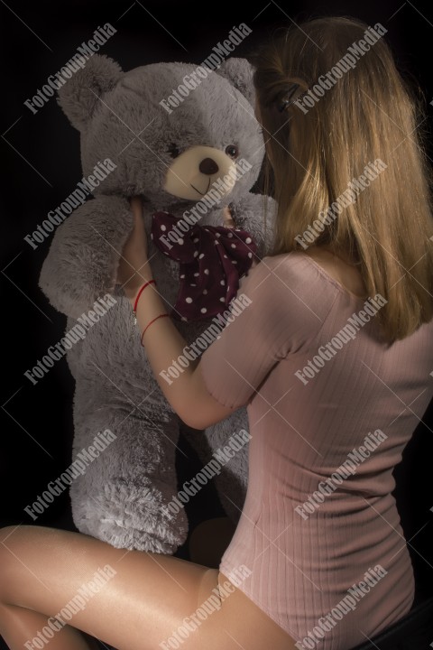 Young girl playing with her huge big teddy bear on floor