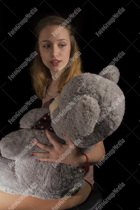 Young beautiful girl hugging big huge teddy bear soft toy happy smiling.