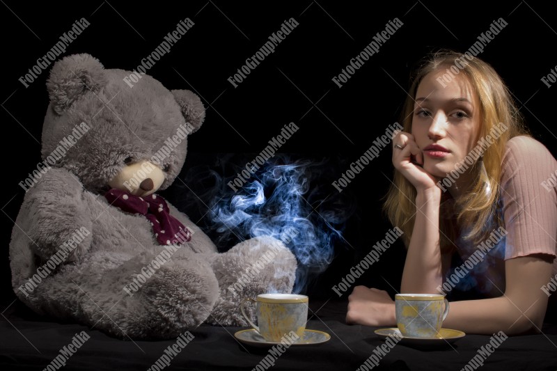 Tea time for young girl and her big teddy bear