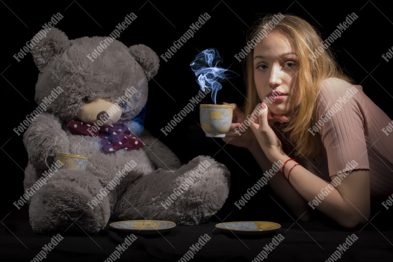 Tea time for young girl and her big teddy bear