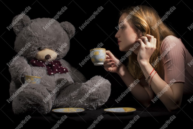 Tea time for young girl and her big teddy bear