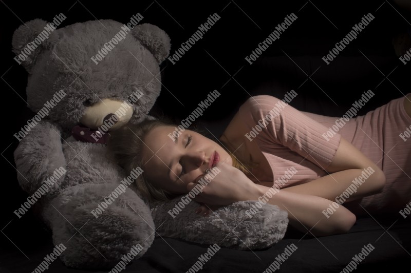 Sleeping on teddy bear soft toy isolated on black baground