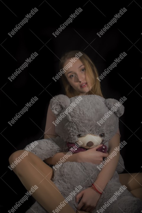 Young beautiful girl hugging big huge teddy bear soft toy happy smiling.