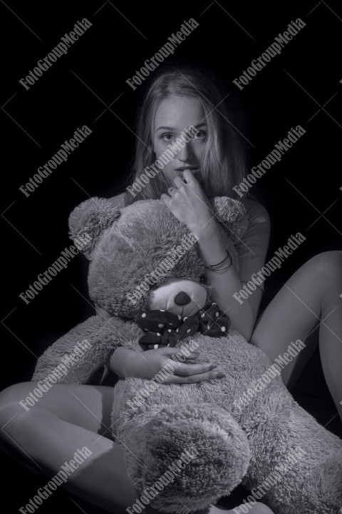 Young girl hugging big huge teddy bear soft toy looking at camera