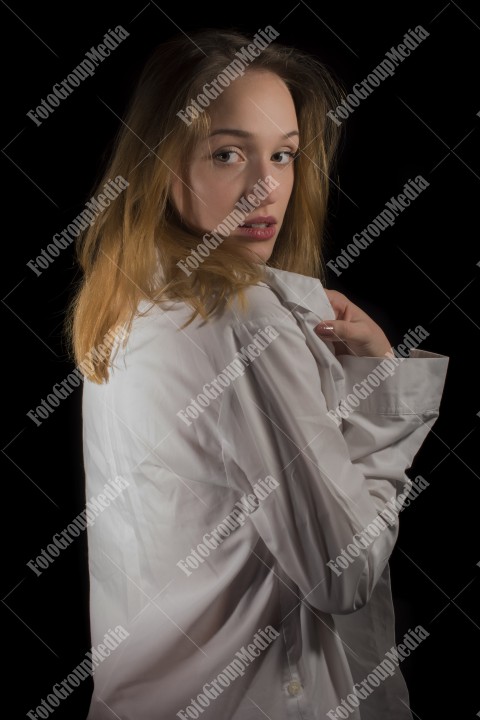 Fashion model posing in studio wearing white shirt on black background