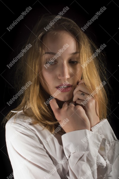 Fashion model posing in studio wearing white shirt on black background