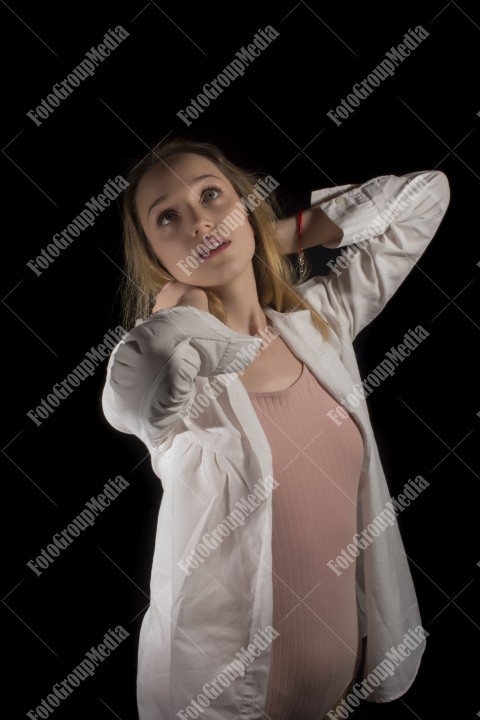 Fashion model posing in studio wearing white shirt on black background